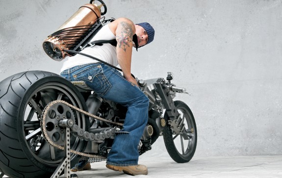 На последней позиции в «Топ-10» оказался этот совершенно «фриканутый» аппарат техасской мастерской RK Concepts (RK – это инициалы ее шефа – Рафика Каисси). Называется это творение RK Chain («Цепь»), и, дабы соответствовать имени, рама и маятник его выполнены из гигантских приводных цепей. 1,2-литровый мотор и коробка передач – Buell. Рейк – 38o. Передняя вилка – устрашающего вида рессорная конструкция. Задняя подвеска – «пневма», как говорят медики. Колеса – Wheels4Choppers (переднее – 19-дюймовое, заднее – 18-дюймовое). Передняя шина – 90-мм Bridgestone, задняя – 360-мм Vee Rubber The Monster. Передний тормоз отсутствует, задний – «бьюлловский», с диском Braking. А знаете, что это за красивенный резервуар, изготовленный из старинного огнетушителя и предназначенный для крепления на спине водителя? Топливный бак! Вот это я понимаю – противоугонная система! Но скажите честно – вам было бы не стремно мчаться на мотоцикле с полной канистрой в рюкзаке? А вот Рафику Каисси, как видите, не стремно. А чего ему бояться? По моим сведениям, он вообще родом из Ливана.